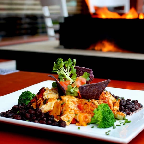 A Votre Santé's healthy chicken and black bean dish with broccoli, guacamole, and tortilla chips.