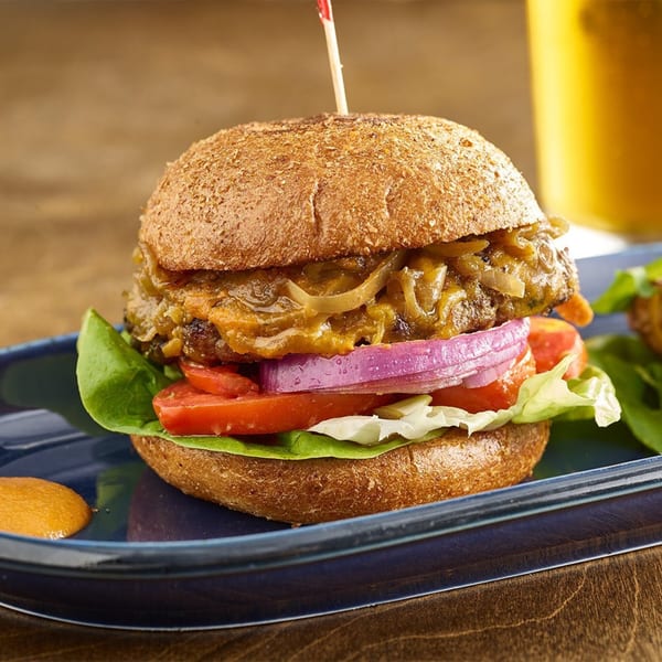 A Votre Santé's healthy burger with caramelized onions, red onion, tomato, and lettuce on a whole wheat bun.