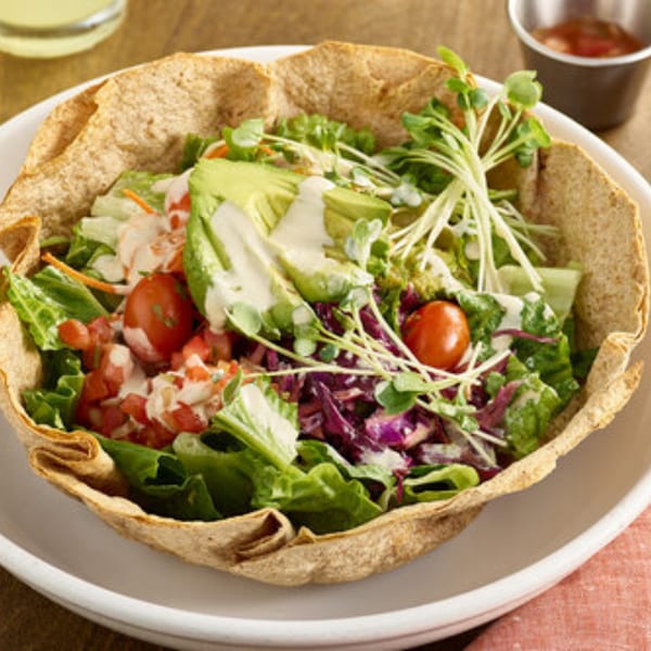 A Votre Santé's healthy taco salad in a crispy tortilla bowl, topped with avocado and dressing.