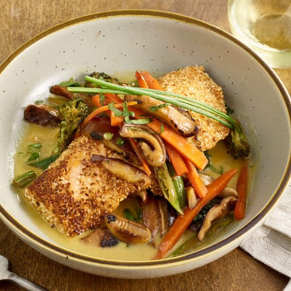 A Votre Santé's sesame-crusted fish with carrots, broccoli, and mushrooms in a light sauce.