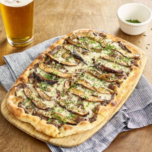 A Votre Santé's healthy mushroom flatbread pizza with cheese and chives, served with beer.